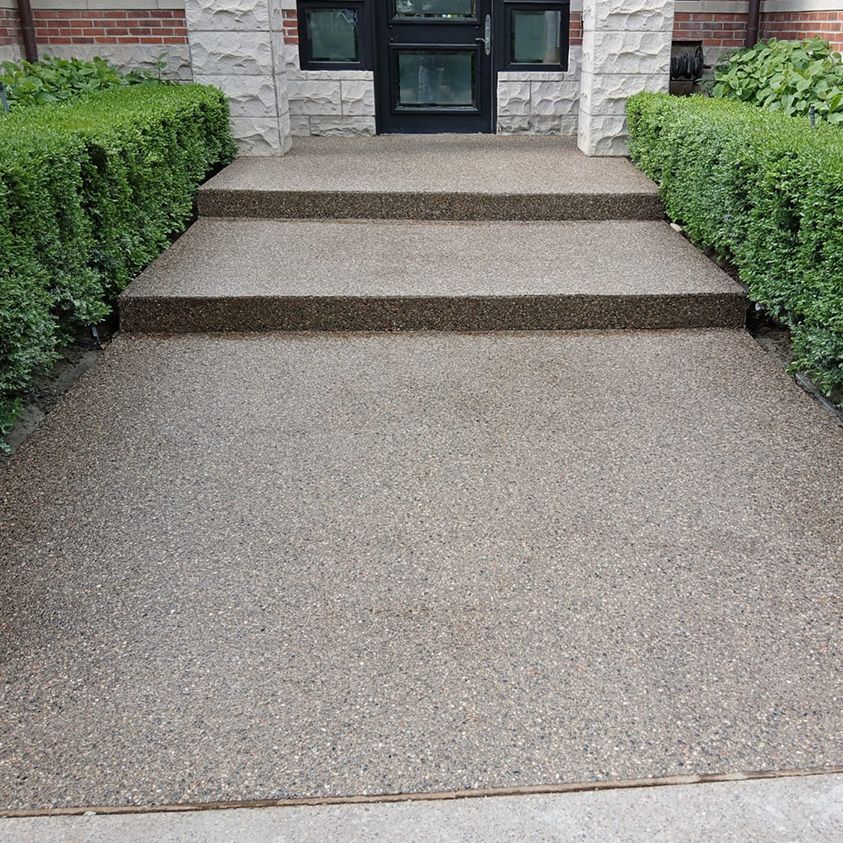 A concrete walkway with steps leading up to a house.