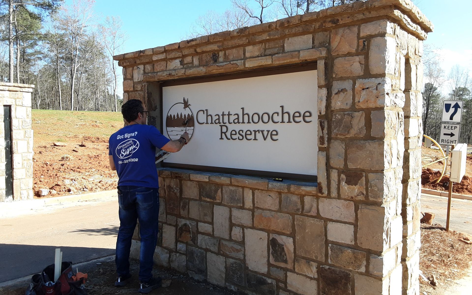 An employee of Advantage Graphics and Signs is installing a monument sign for an apartment complex