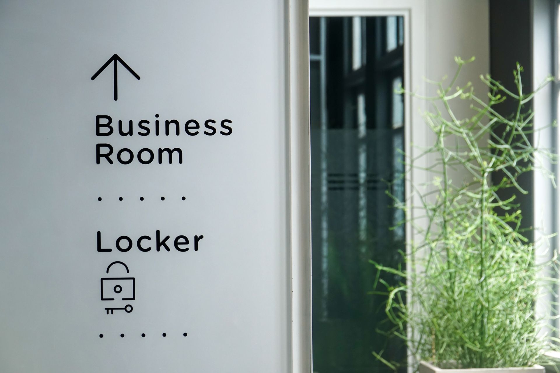 Wall sign showing directions to the business room and locker area in a modern office.