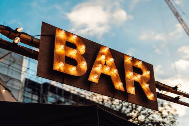 View from the ground up of a sign saying “BAR” against a blue evening sky.
