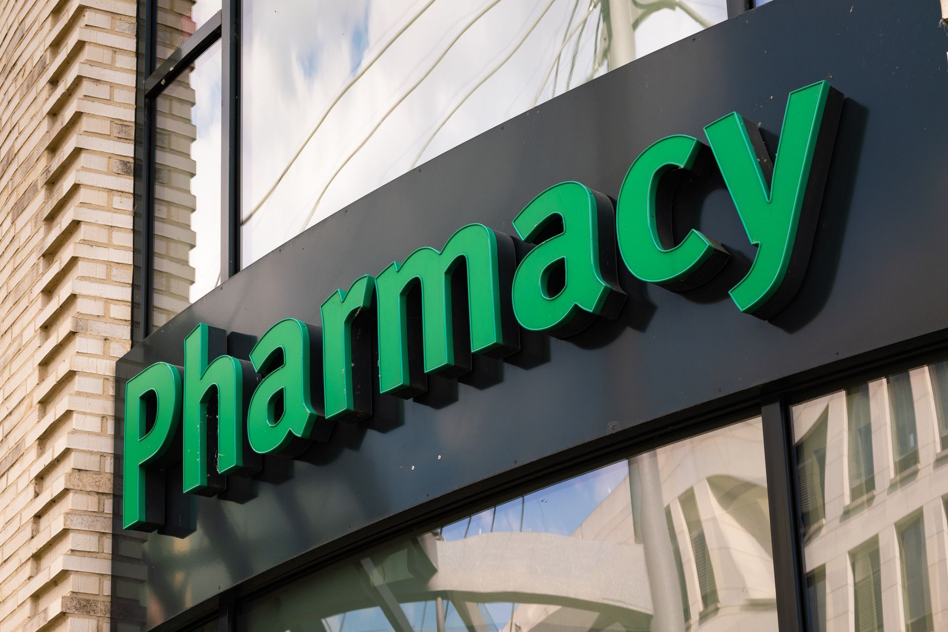 Pharmacy logo sign on a building facade in big green colored letters. Pharmacy logo sign on a building facade in big green colored letters.