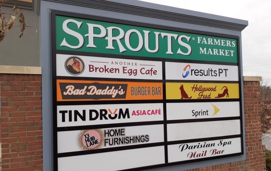 Sign for a shopping center with the Sprouts Farmers Market logo, along with other store names.