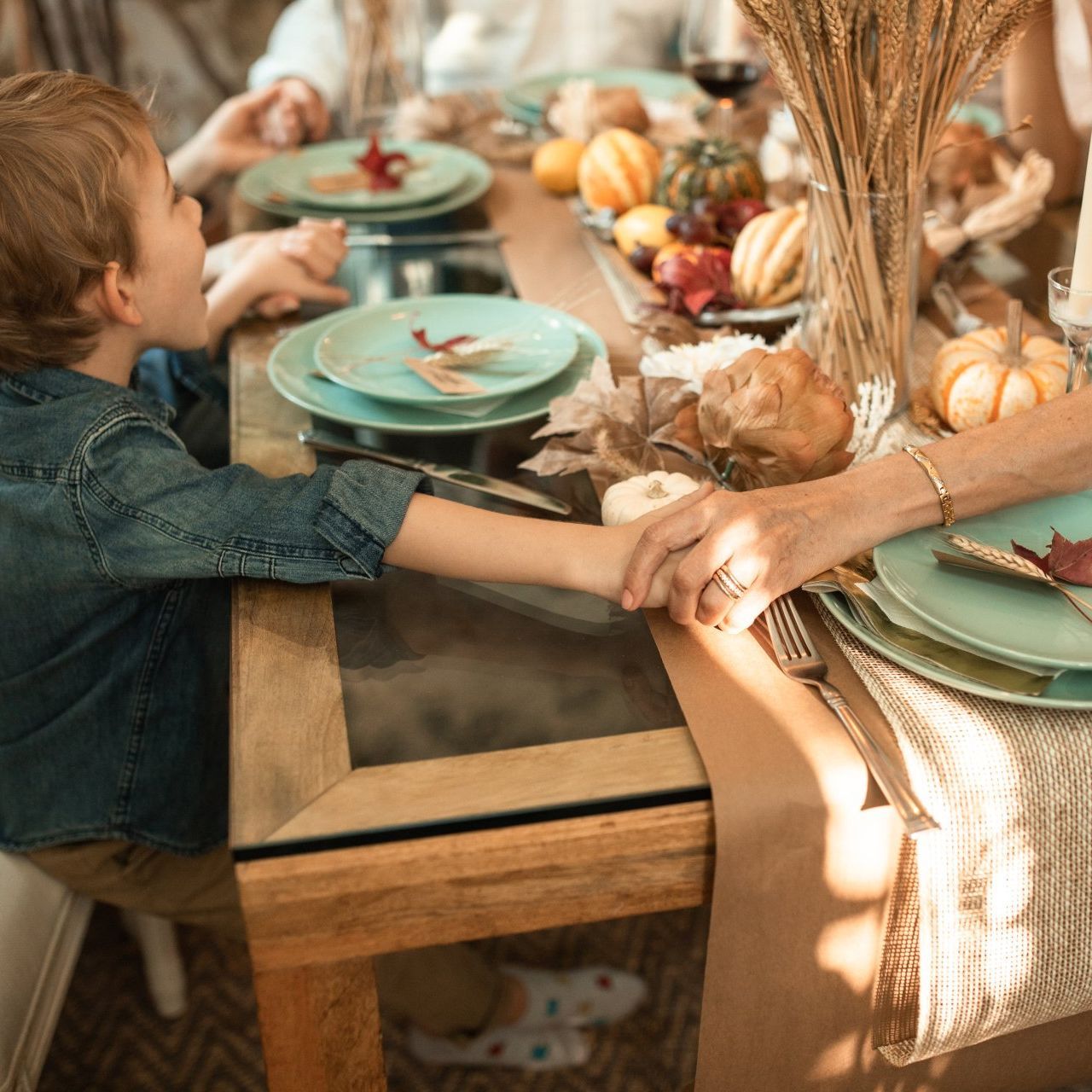 Image of child holding hands with elder at Thanksgiving meal.