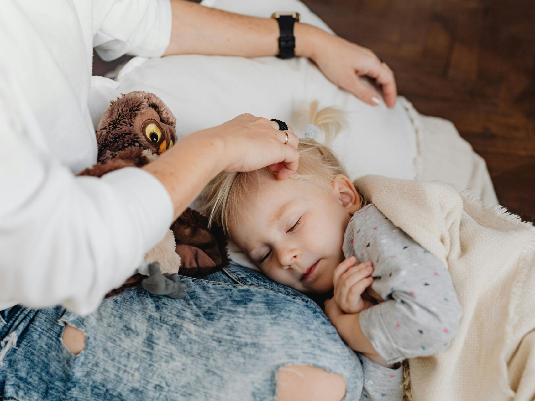 Sick child with mother rubbing her head to help her feel better.