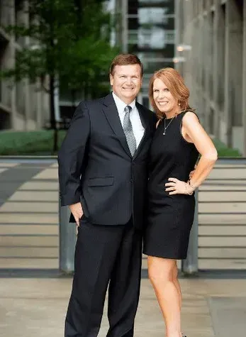 A woman is sitting at a desk with a laptop and a book.