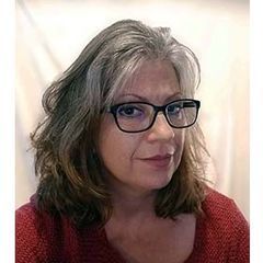 A woman wearing glasses and a red sweater is looking at the camera.