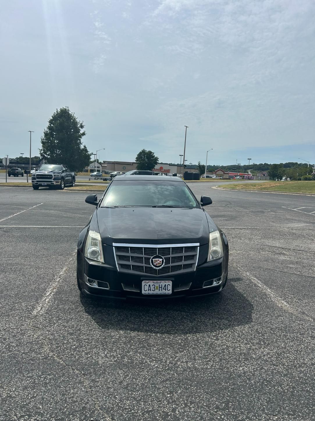 Black Cadillac sedan parked in an asphalt parking lot on a sunny day.