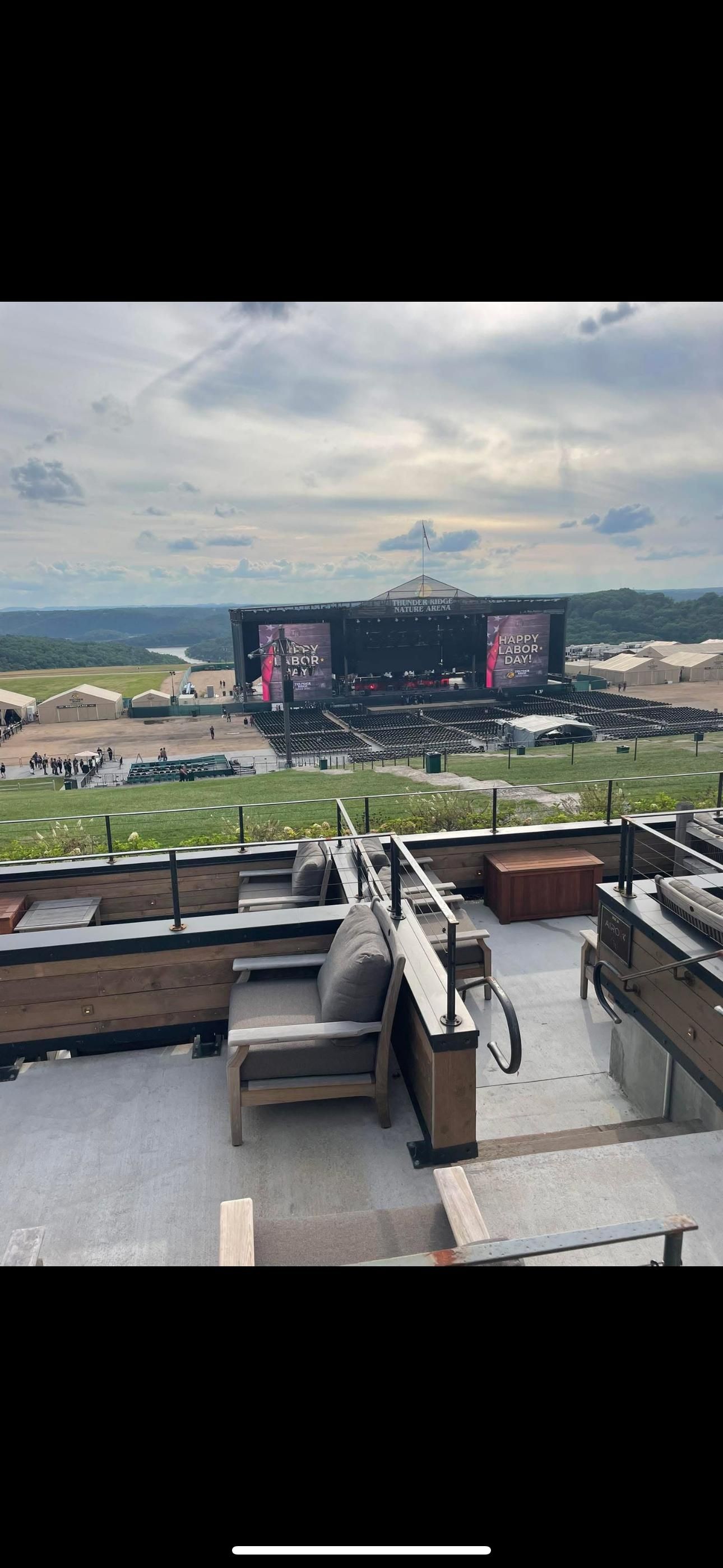 Overhead view of a music festival stage with a rooftop seating area in the foreground.