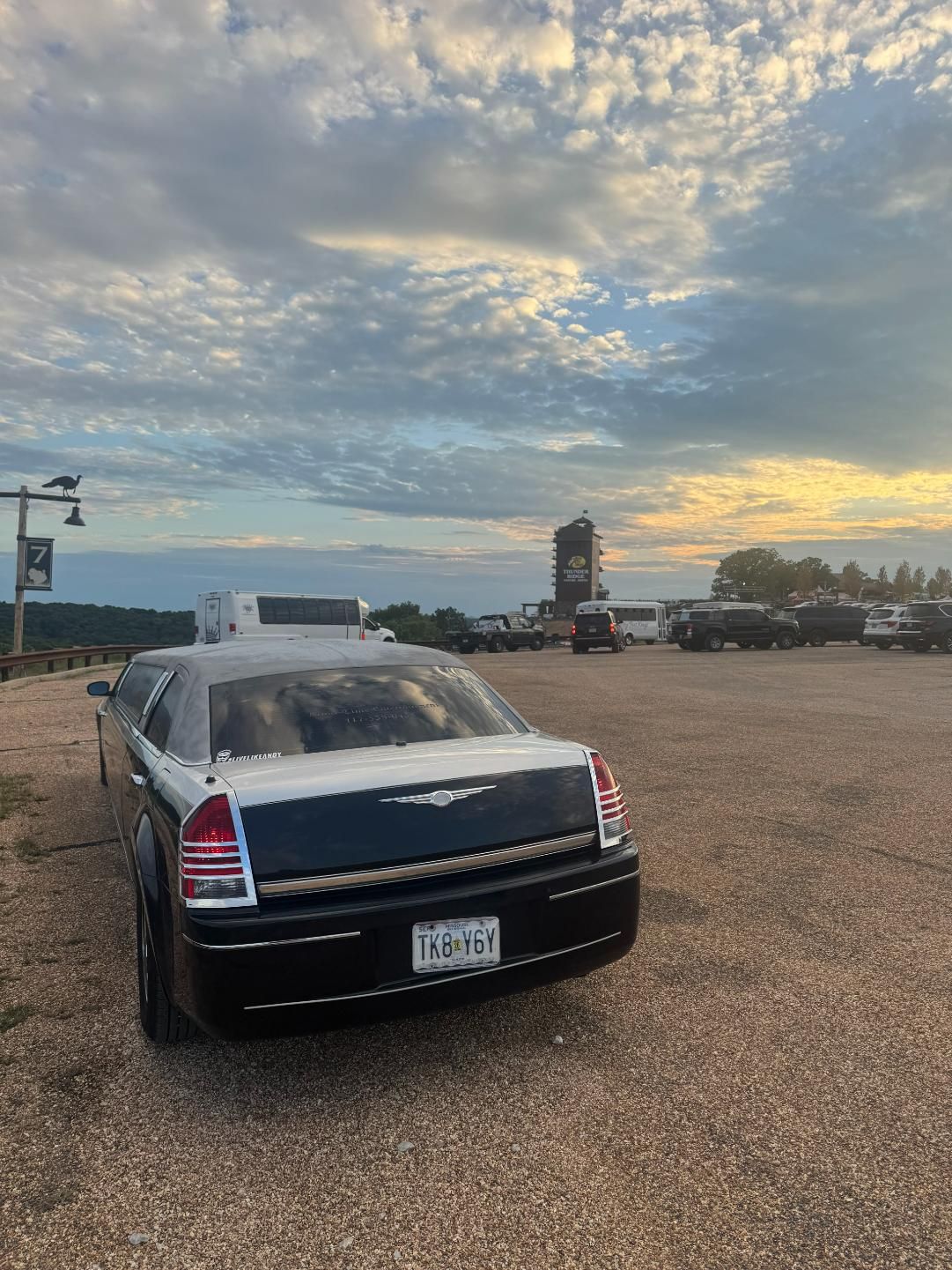 Chrysler 300 limousine in a gravel parking lot at dusk with a cloudy sky overhead.