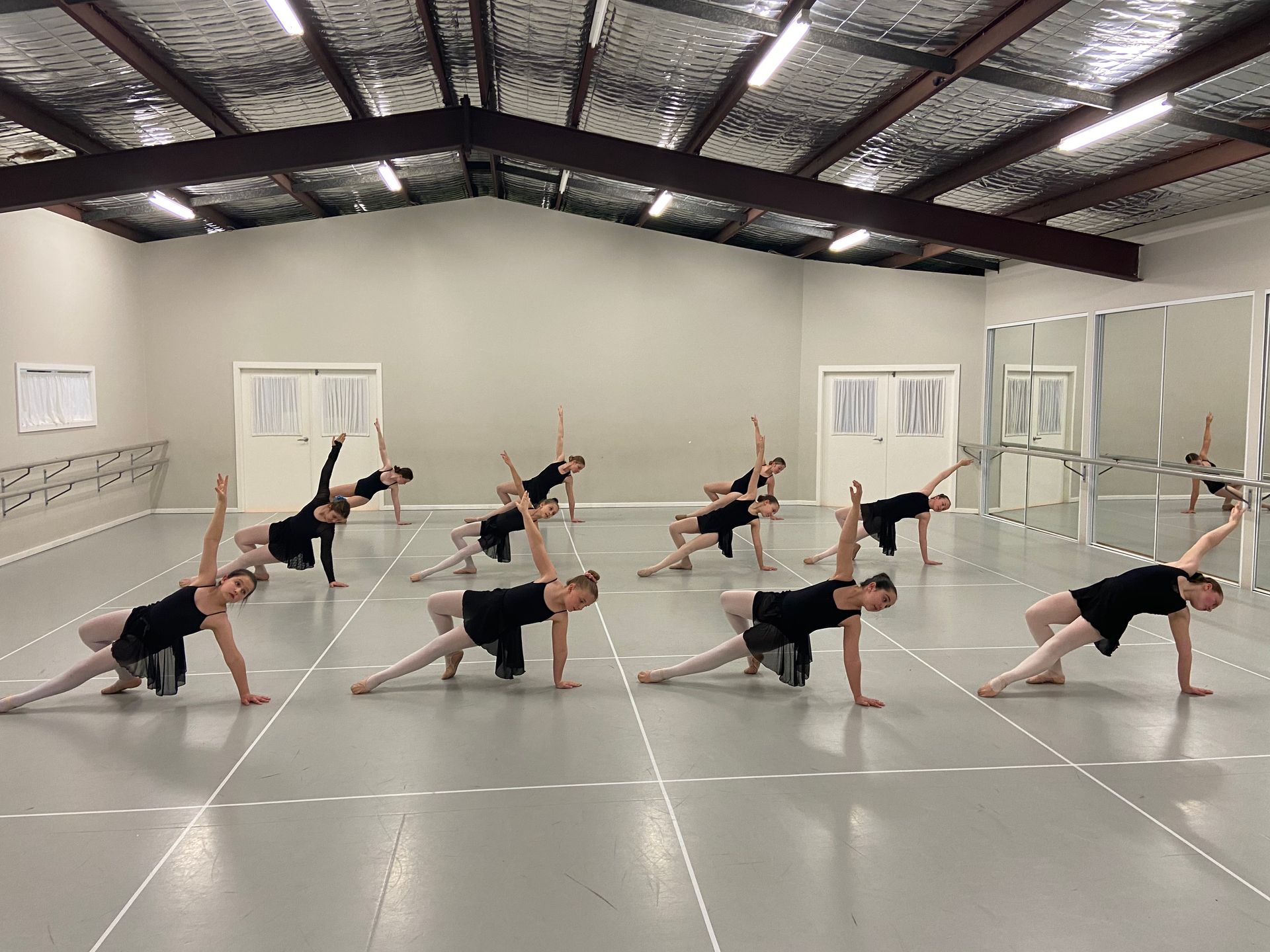 A group of dancers are practising in a dance studio.