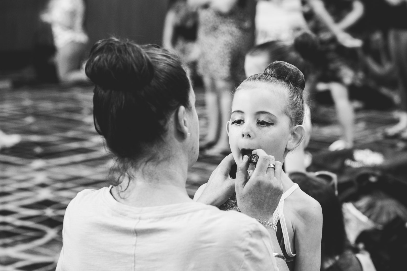 A woman is applying makeup to a little girl 's face in a black and white photo — Studi-O Dance School In Gateshead, NSW