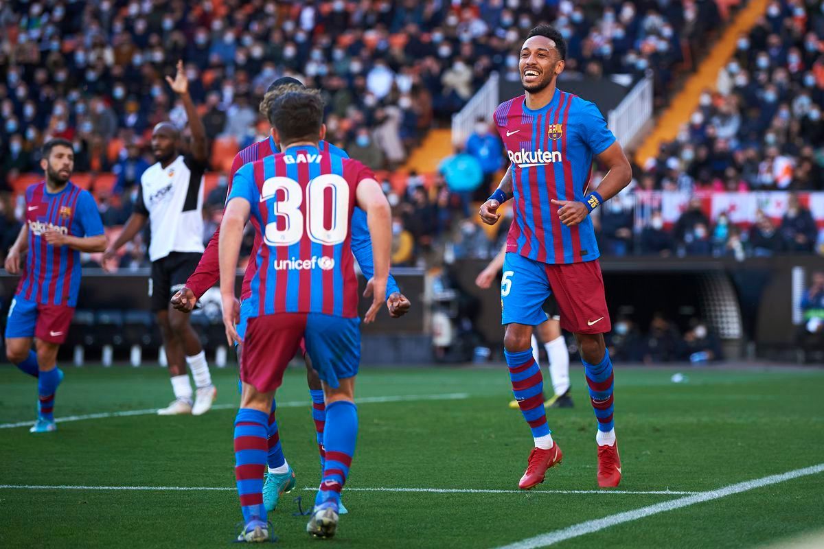 A group of soccer players are celebrating a goal on a soccer field.