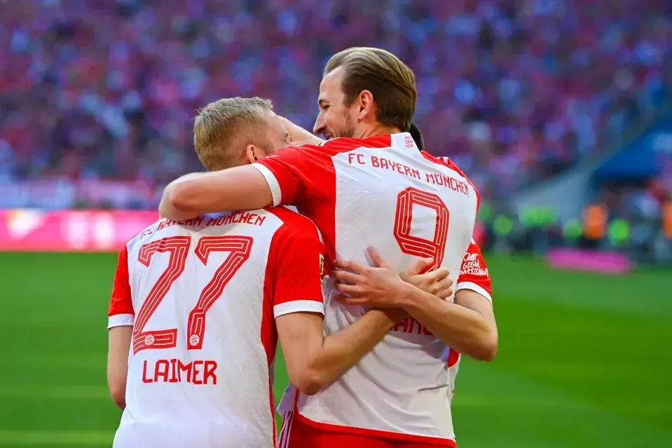 Two soccer players are hugging each other on the field.