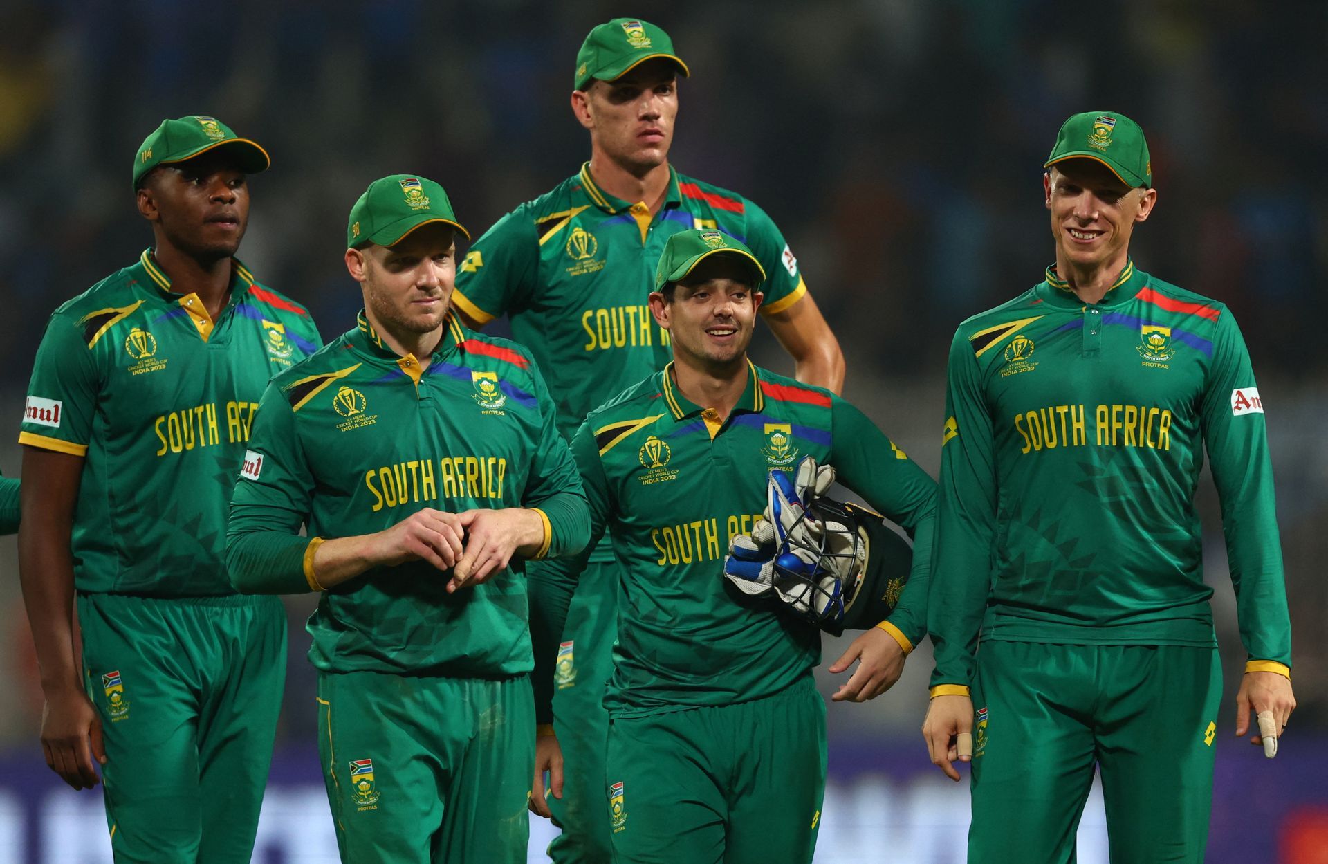 A group of cricket players are standing next to each other on a field.
