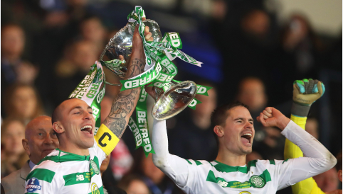 Two soccer players holding up a trophy that says be proud