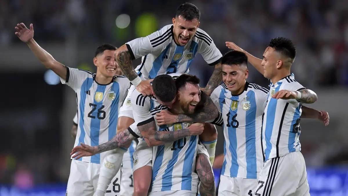 A group of soccer players are celebrating a goal on a field.