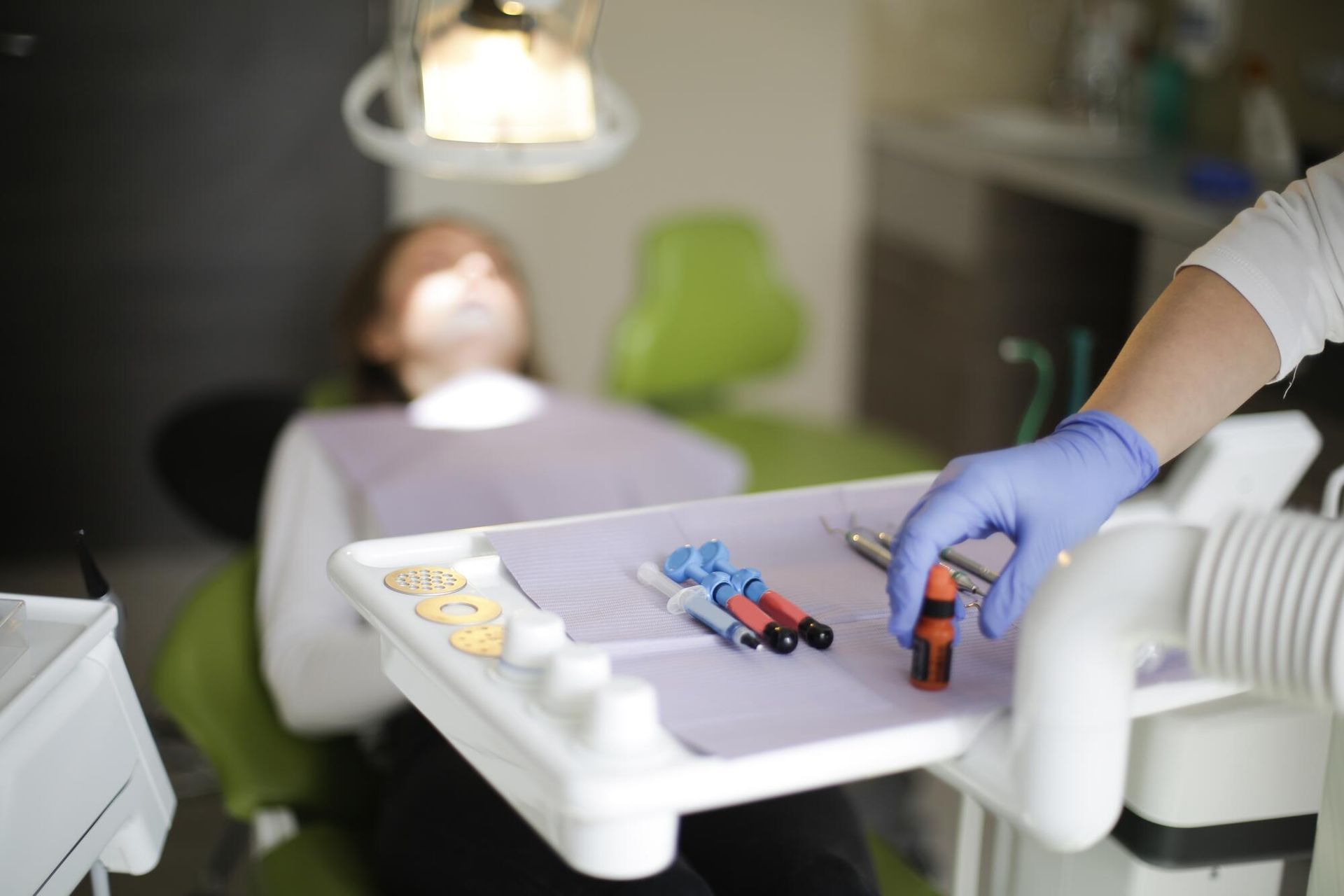 A dentist is holding a syringe in front of a patient in a dental chair.