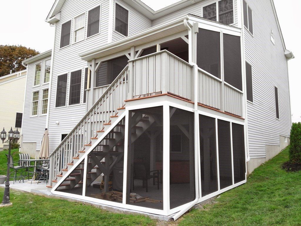 A white house with a screened in porch and stairs.