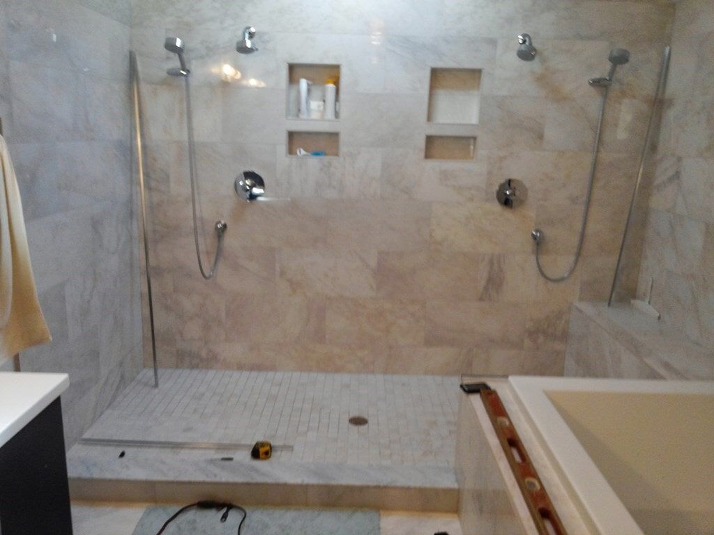 A bathroom with two showers and a bathtub