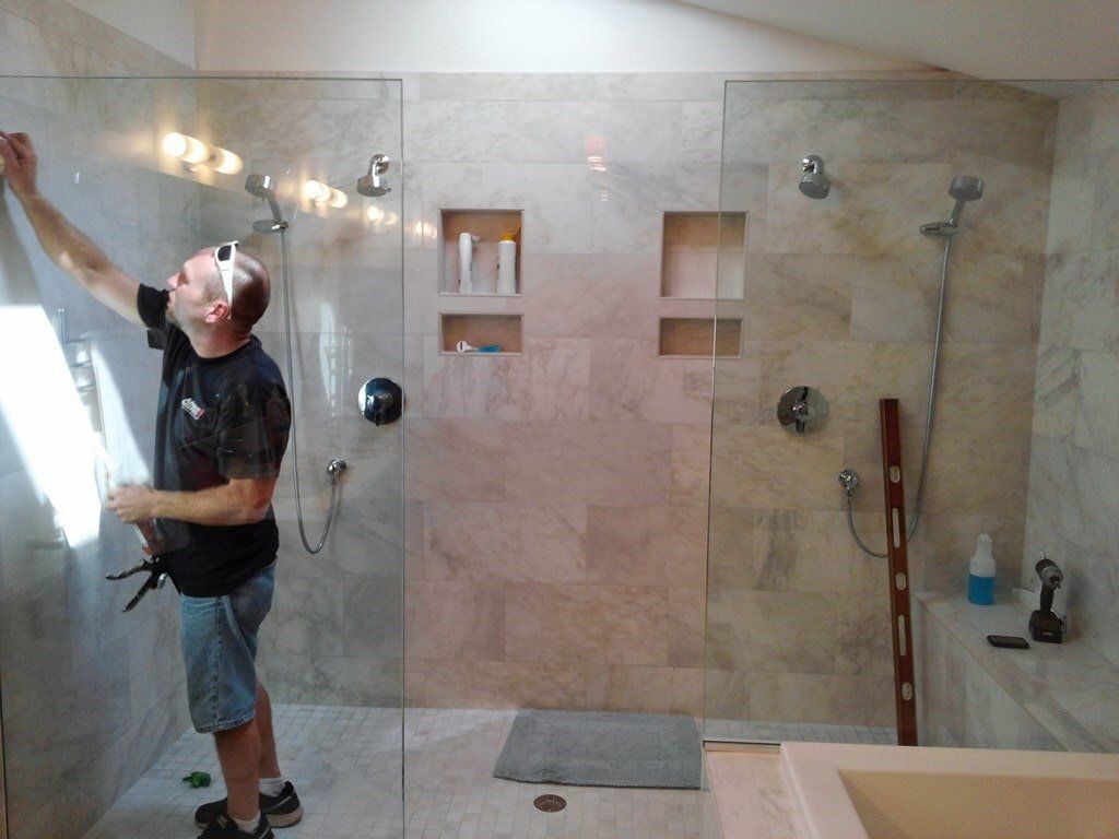 A man is installing a shower door in a bathroom.