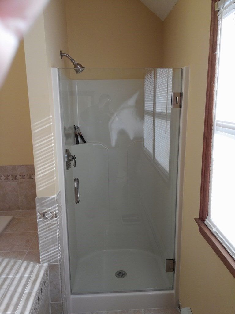 A bathroom with a glass shower door and a window.