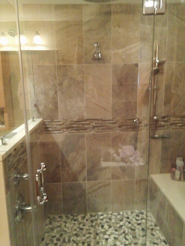 A bathroom with a walk in shower with a glass door