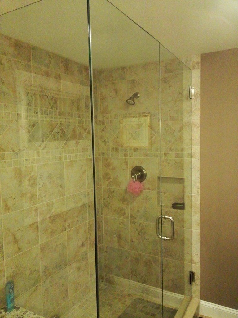 A bathroom with a walk in shower with a glass door.