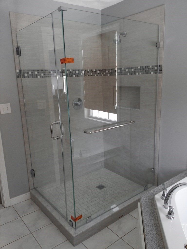 A bathroom with a glass shower door and a bathtub.