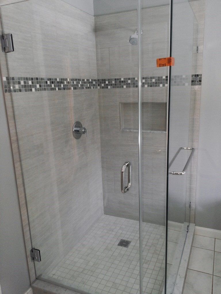 A bathroom with a walk in shower with a glass door.