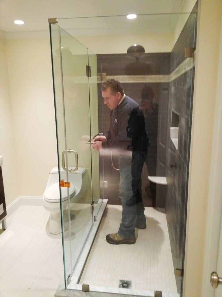 A man is standing in a bathroom looking at his phone.