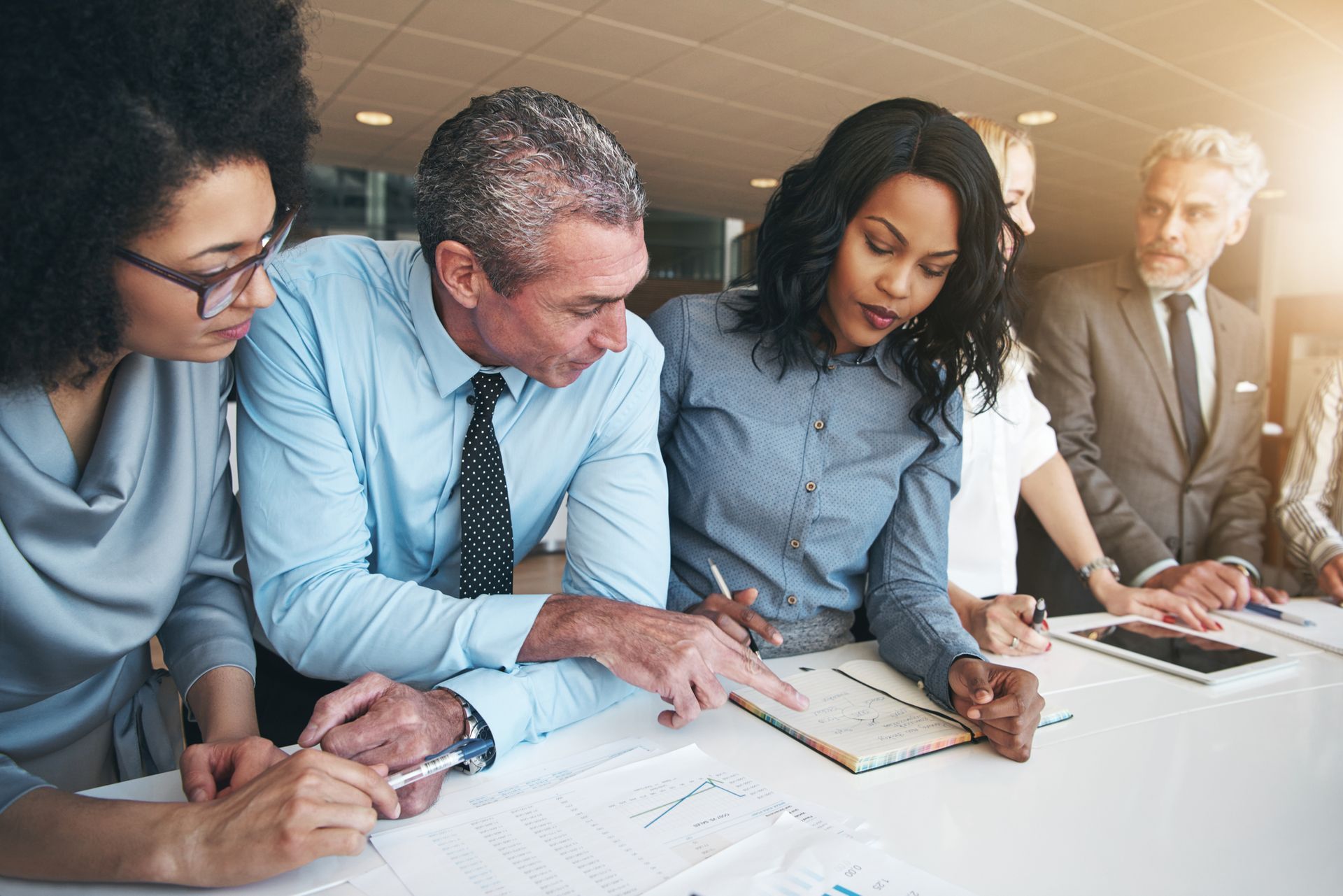 Business team reviewing documents at a table; pointing and discussing.
