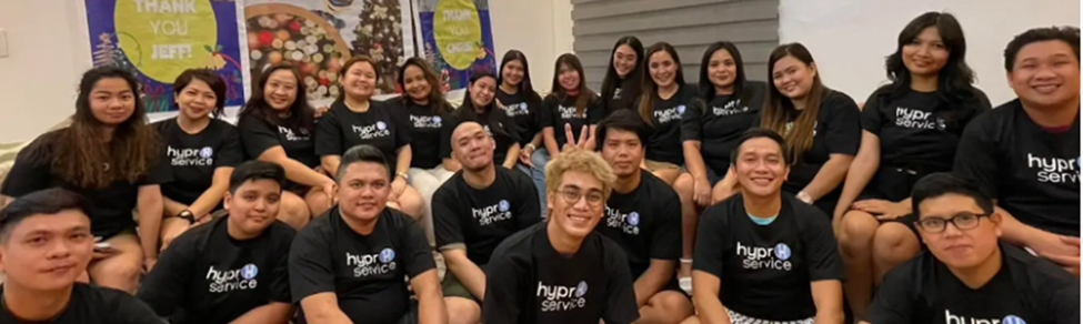 Two people shaking hands, indoors, one in a suit, one in a blue shirt.