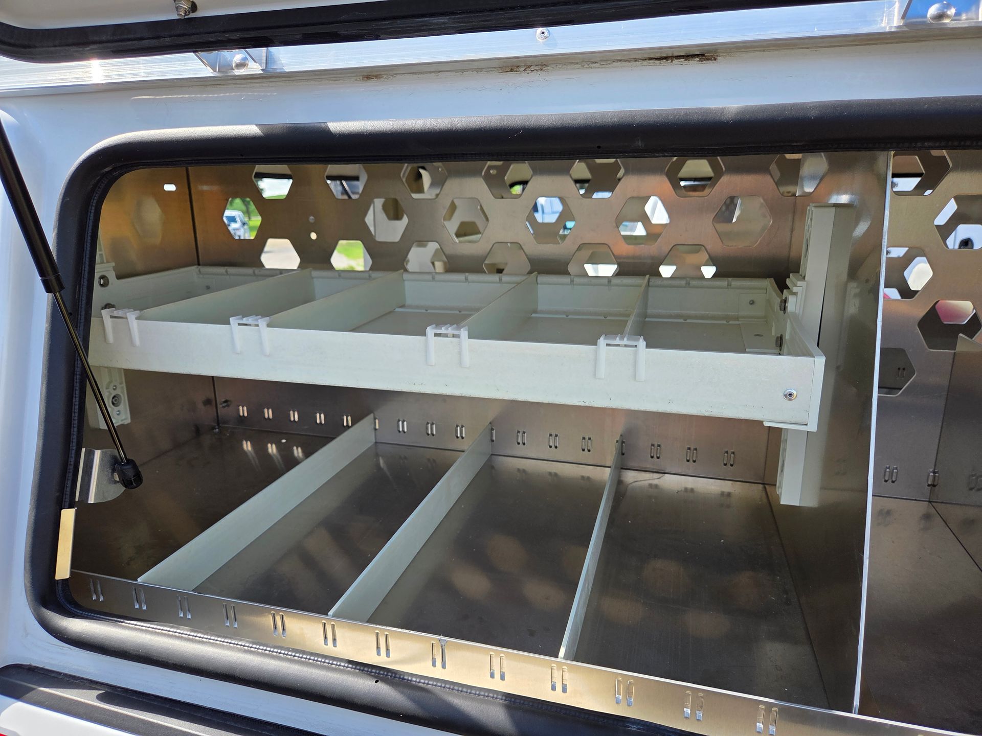 Interior of a white truck bed storage unit with shelves and dividers.