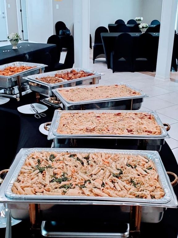 There are many trays of food on the table.