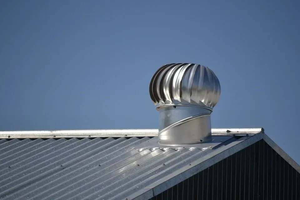 Metal Roof With a Rotating Turbine Vent Against a Clear Blue Sky — Far North Plumbing in Mourilyan, QLD