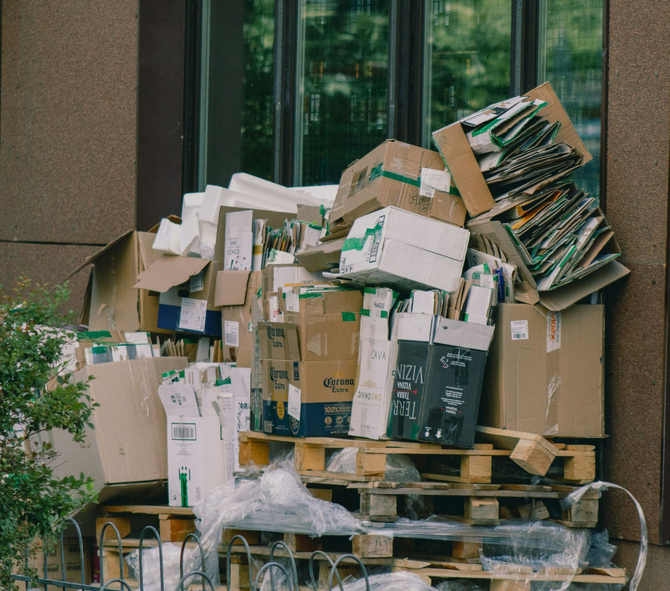 Overflowing cardboard boxes and bundled recycling stacked on a pallet outside a building