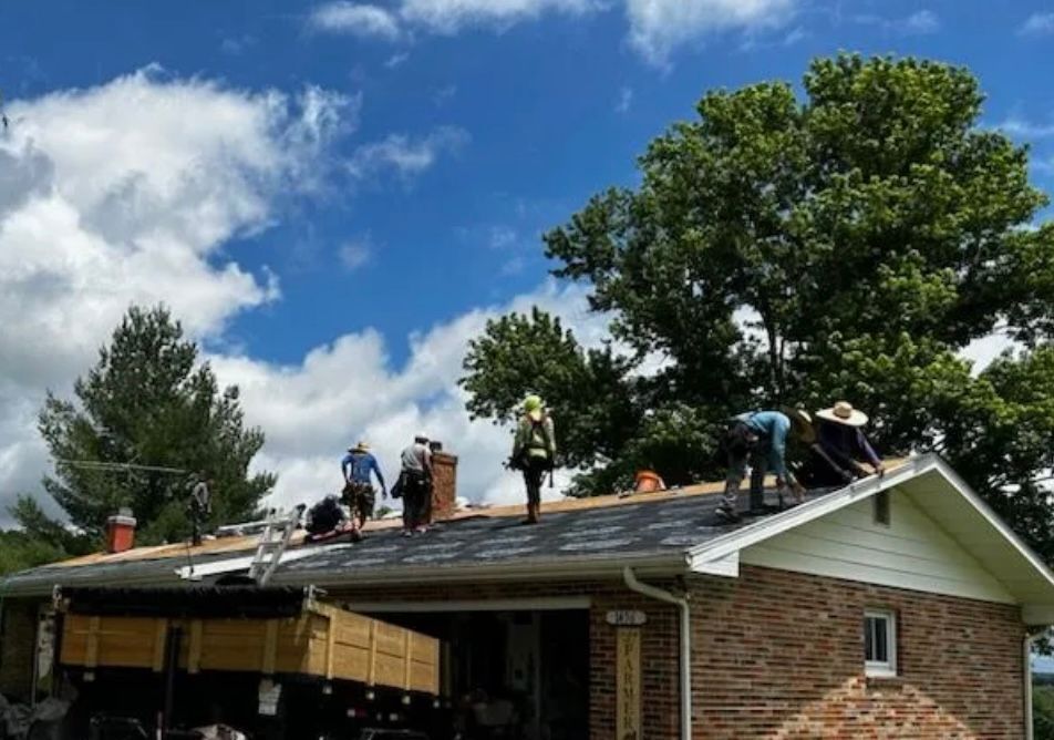 A group of people are working on the roof of a house.