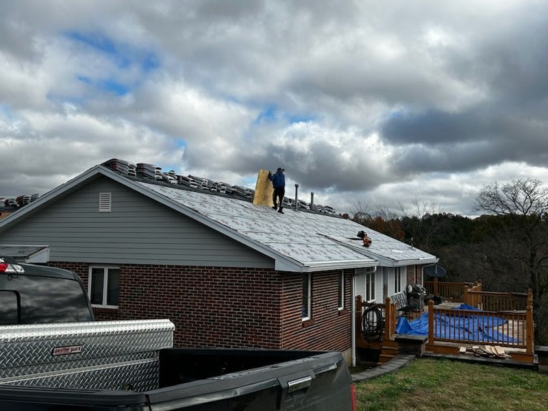 A man is standing on the roof of a house.