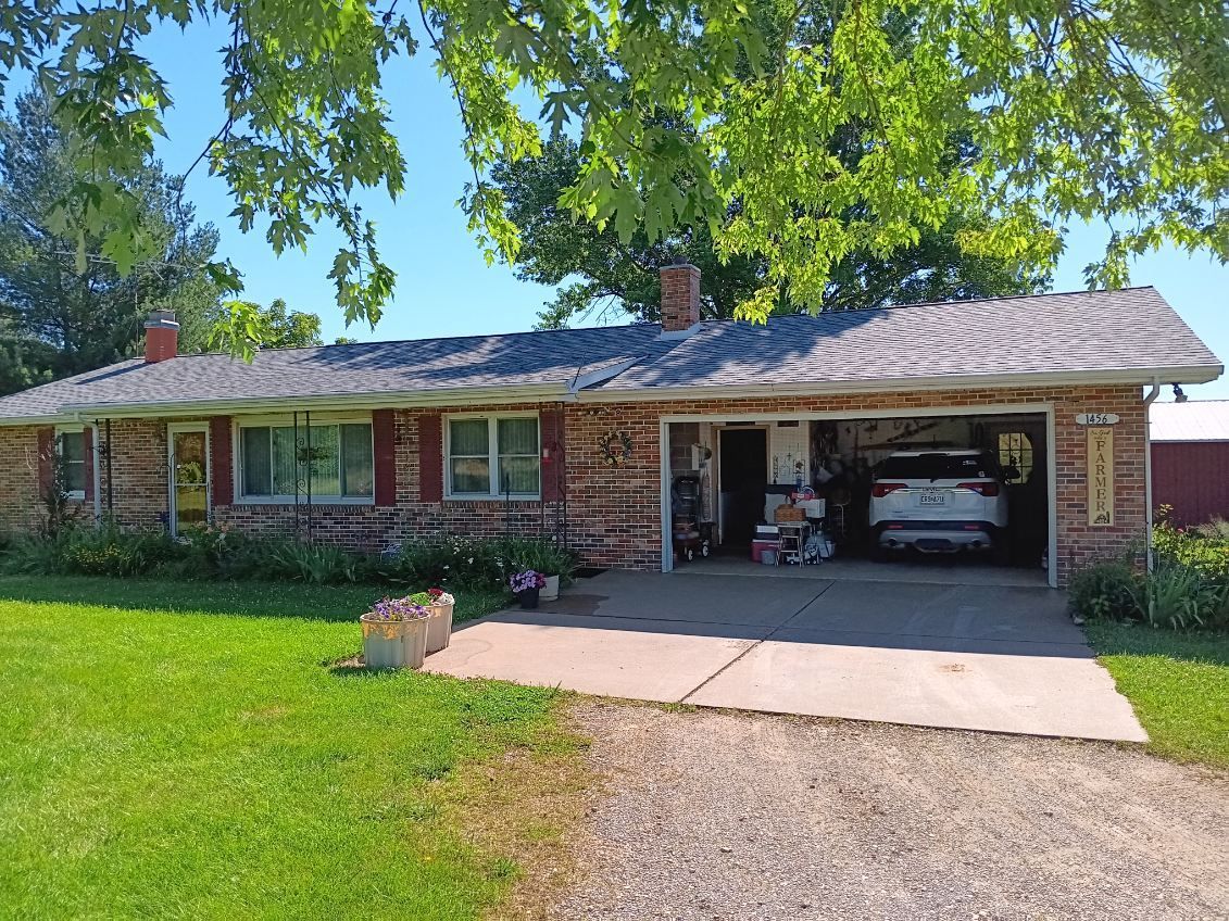 A brick house with a car parked in the garage.