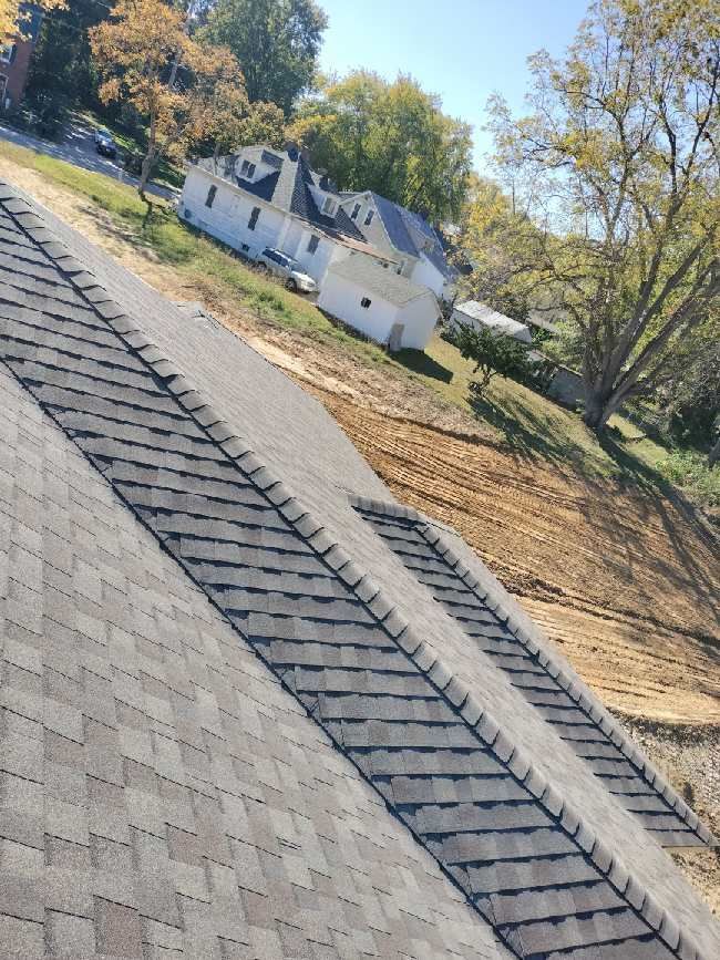 A roof with a lot of shingles on it and a house in the background.