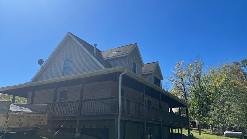 A large house with a large deck and a blue sky in the background.