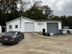 A black car is parked in front of a white garage.