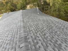 A roof with a lot of shingles on it and trees in the background.
