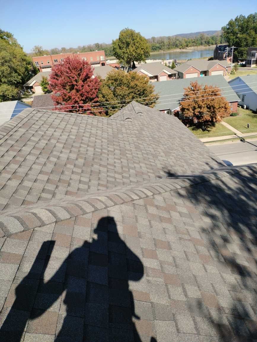 A shadow of a person is cast on the roof of a house.