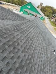 A close up of a roof with a green building in the background.