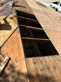 A hole in the roof is being filled with plywood.