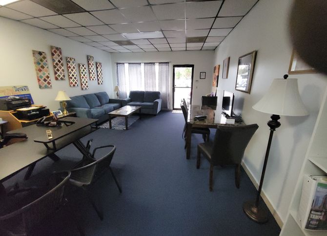 Office with blue carpet, couches, desks, and a door to the outside.