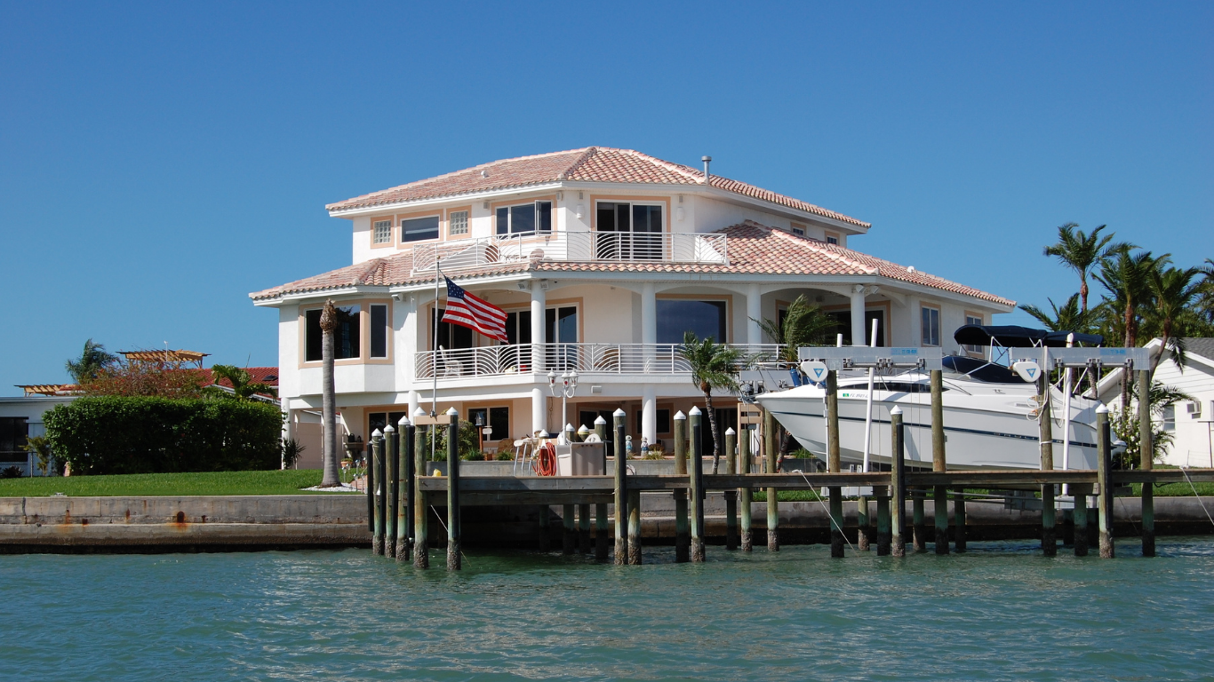 Blue Craftsman home with stone accents, a brick walkway, and a manicured lawn.