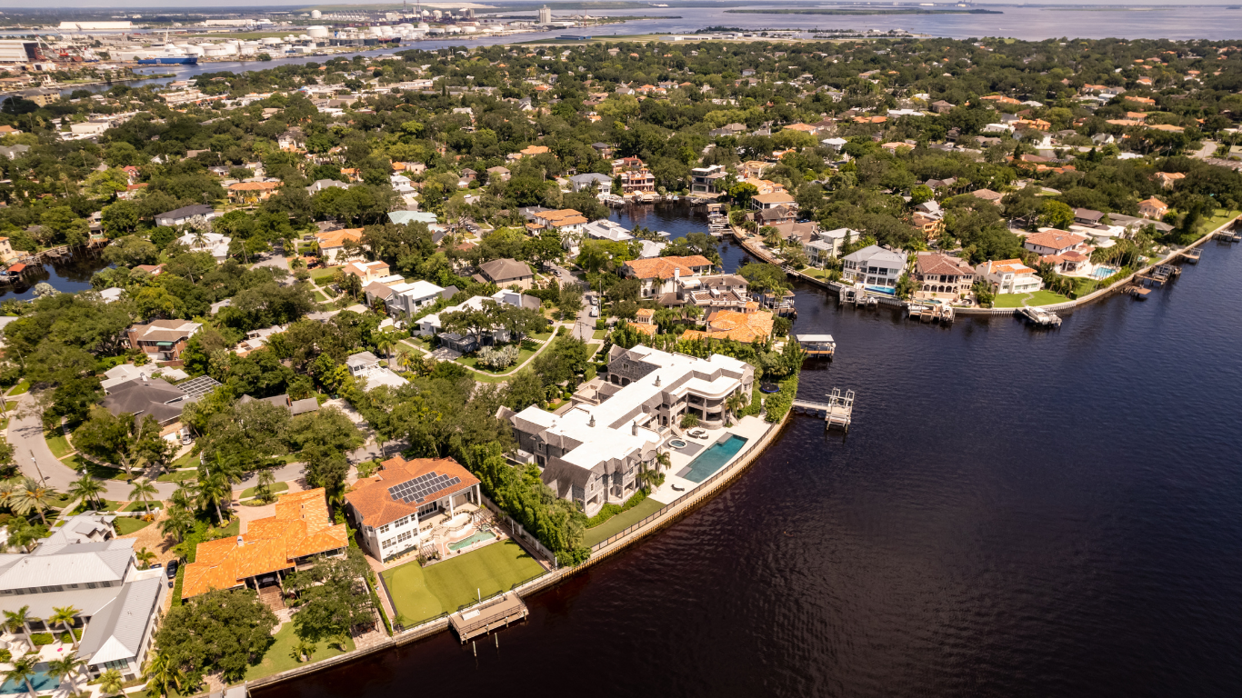 Modern two-story house with a pool. White and gray exterior, large windows, and a balcony.