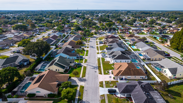 Aerial view of suburban homes with colorful fall foliage along curved streets.